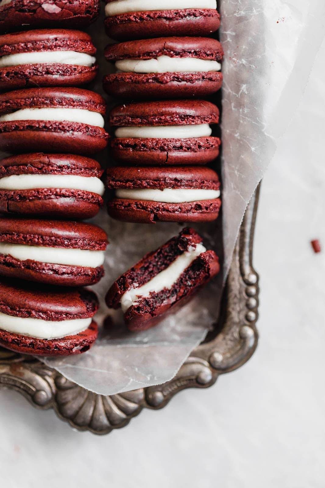 A half eaten macaron lays next to other cookies.